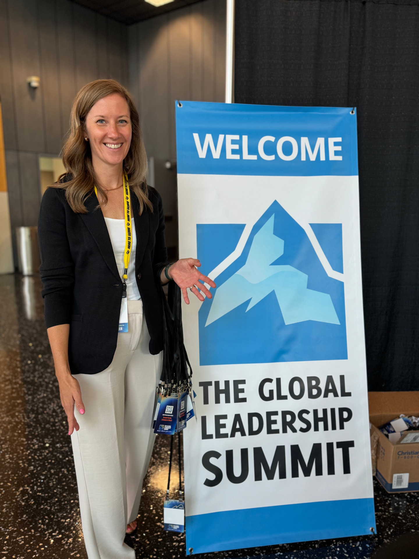 Mission-Driven Marketing team member welcoming attendees beside a Global Leadership Summit sign
