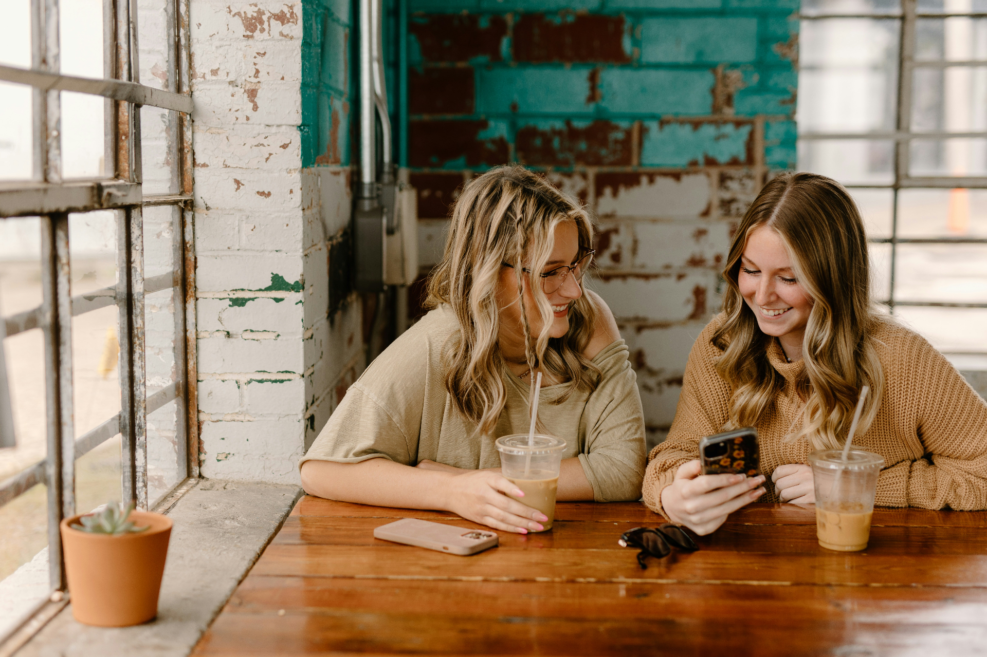 Two women looking at a phone together at a coffee shop