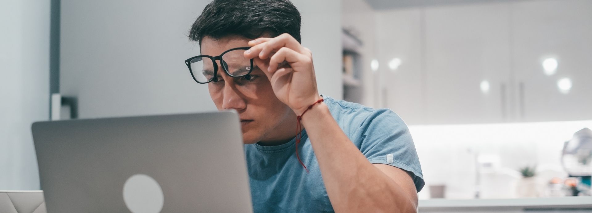 Person squinting at a laptop screen while searching online