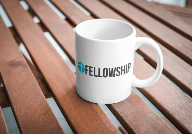Fellowship branded mug on a wooden table
