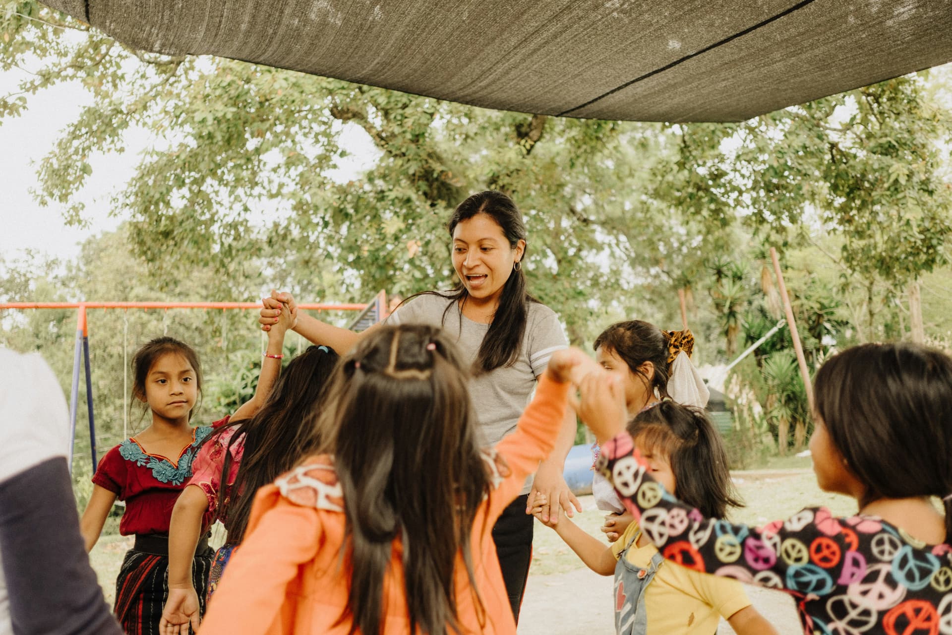 A community leader playing a circle game with a group of children outdoors