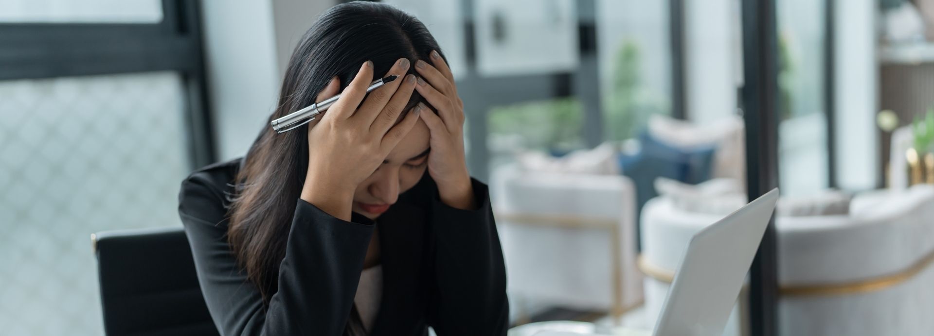 Overwhelmed professional holding their head in front of a laptop